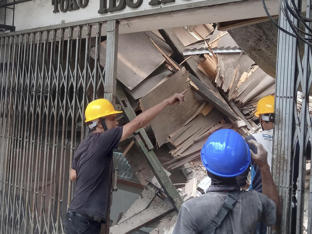 Workers inspect a store damaged during an earthquake in Cianjur, West Java, Indonesia, Monday, Nov. 21, 2022.