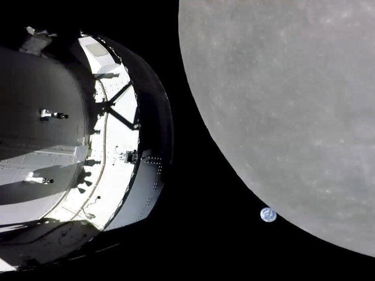 This screengrab from NASA TV shows NASA's Orion capsule, left, nearing the moon, right, on Monday. At center is Earth.