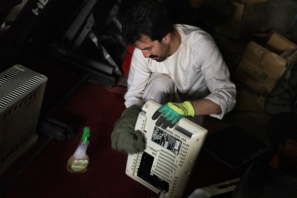 Siraj Zamanzai cleans used electronics at a shop. He was unemployed for a year before finding this job.