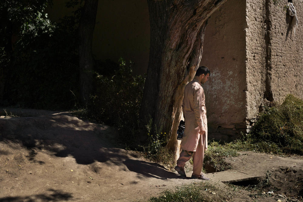 Near the orchard, Mohammad Hashim walks past buildings that show signs of damage from the war.