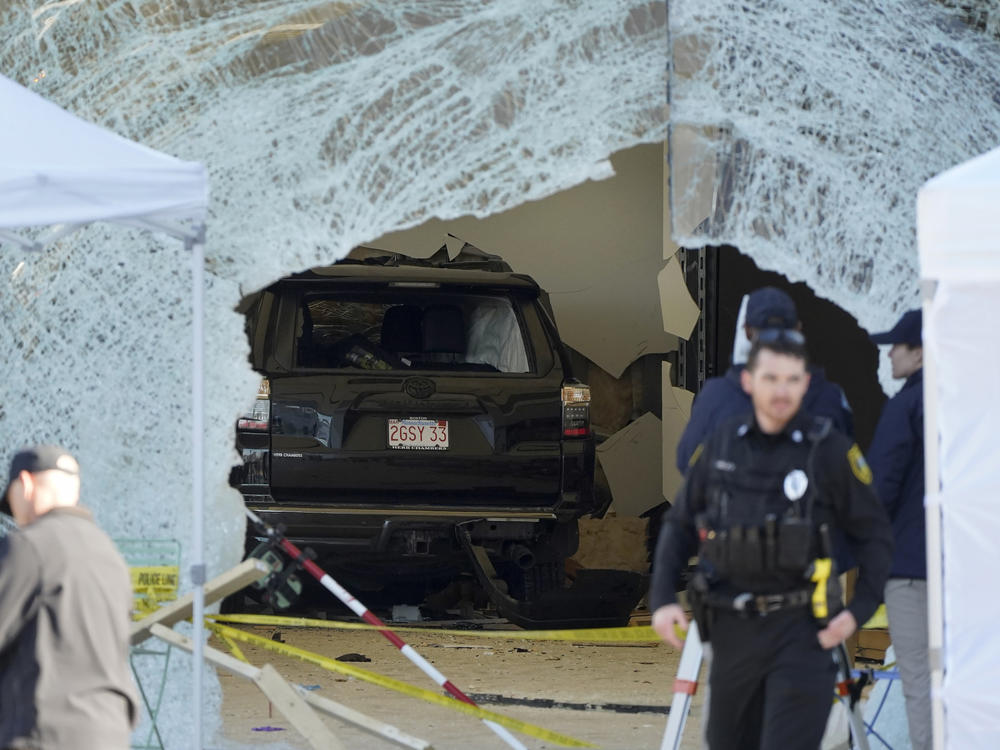 An SUV sits inside an Apple store behind a large hole in the glass. One person was killed and 16 others were injured Monday when the SUV crashed into the store, authorities said.