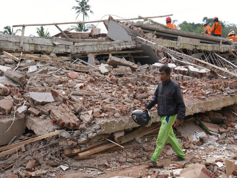 Enjot, 45, who lost his house and some of his relatives, walks on Tuesday past the rubble of a building collapsed in Monday's earthquake in Cianjur, West Java, Indonesia.