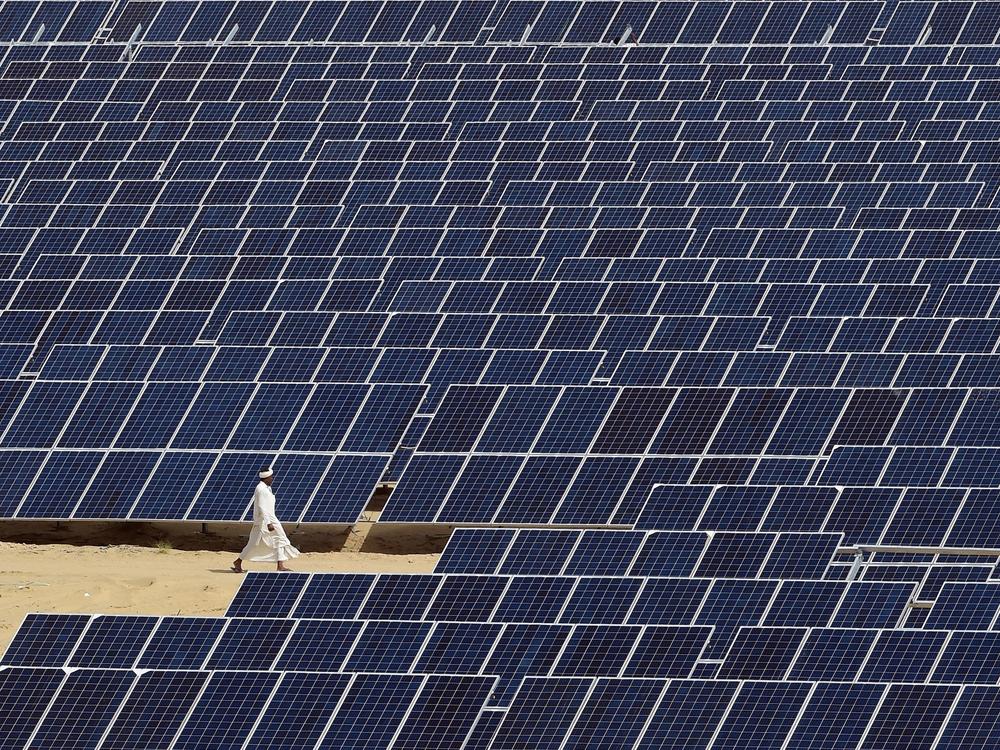 A worker walks past lines of solar panels at the Roha Dyechem solar project in the western northwest Indian state of Rajasthan.