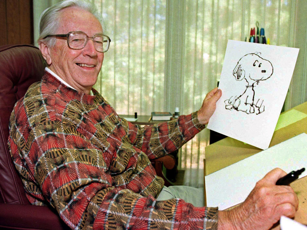 Cartoonist Charles Schulz poses with a sketch of Snoopy in his office in Santa Rosa, Calif. Schulz, who died shortly after his retirement in 2000, would have turned 100 on Nov. 26.