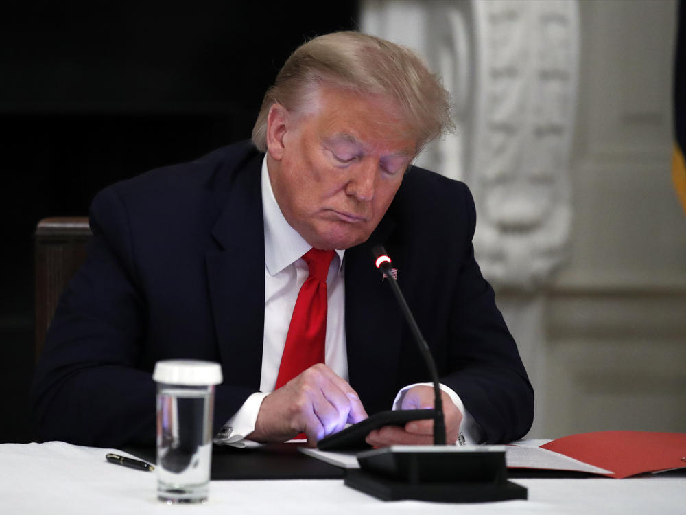 Former President Donald Trump looks at his phone during a roundtable with governors in the State Dining Room of the White House in Washington, June 18, 2020.