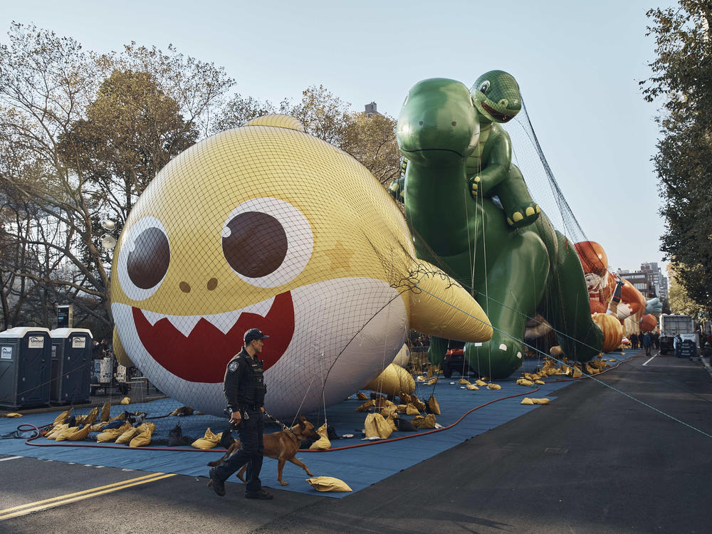 Police walk by inflated helium balloons of Baby Shark and Sinclair's Dino ahead of the Macy's Thanksgiving Day Parade.