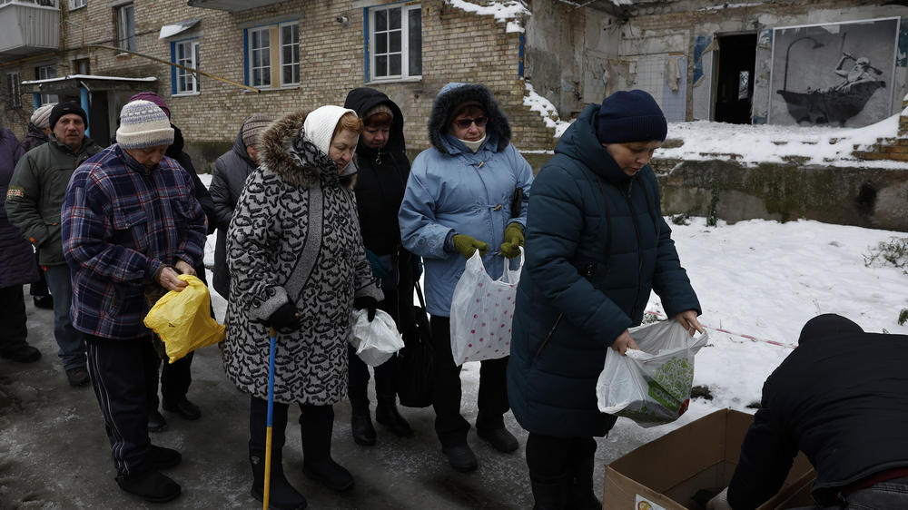 Ukrainians line up for food near a painting by graffiti artist Banksy on a the wall of a destroyed building in Horenka, Ukraine, outside the capital Kyiv.