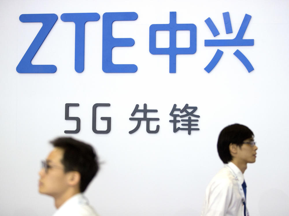In this Sept. 26, 2018 file photo, visitors walk past a display from Chinese technology firm ZTE at the PT Expo in Beijing.