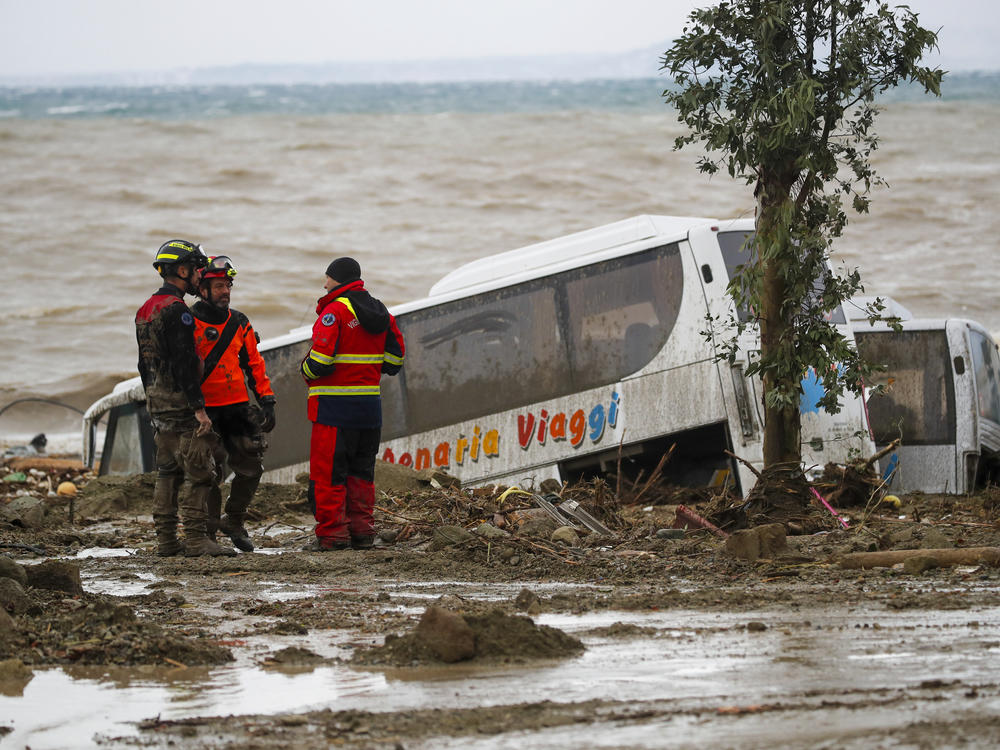 Rescuers stand next to a bus carried away after heavy rainfall triggered landslides that collapsed buildings and left as many as 12 people missing, in Casamicciola, on the southern Italian island of Ischia, Italy, on Saturday.