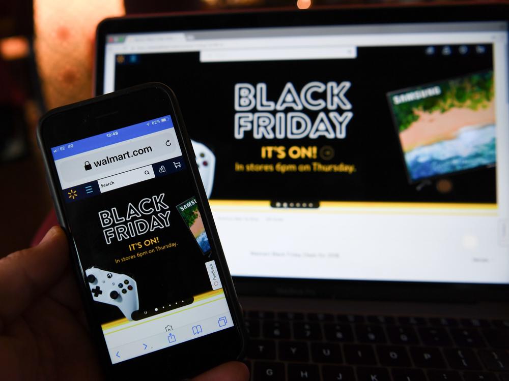 A picture taken in Liverpool, north west England on November 22, 2018 shows Black Friday sales branding on shopping websites displayed on smartphone and laptop screens.