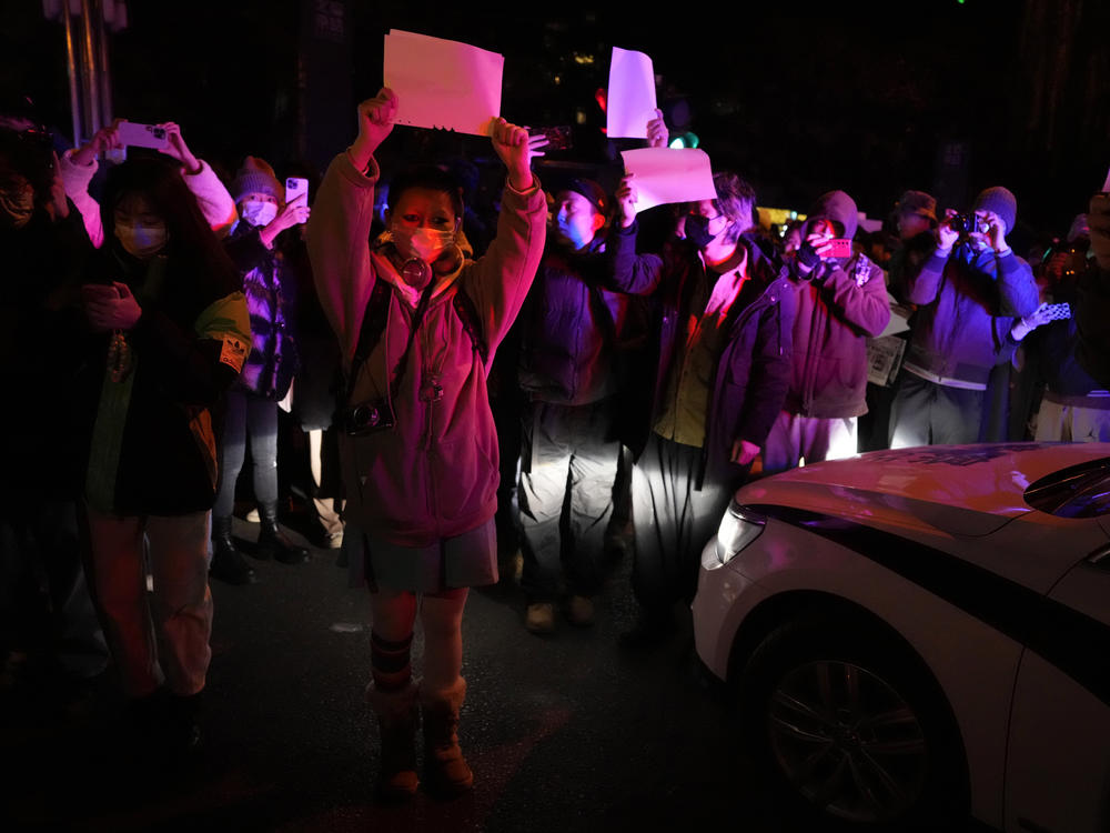 Protesters hold up blank papers and chant slogans as they march in protest in Beijing.