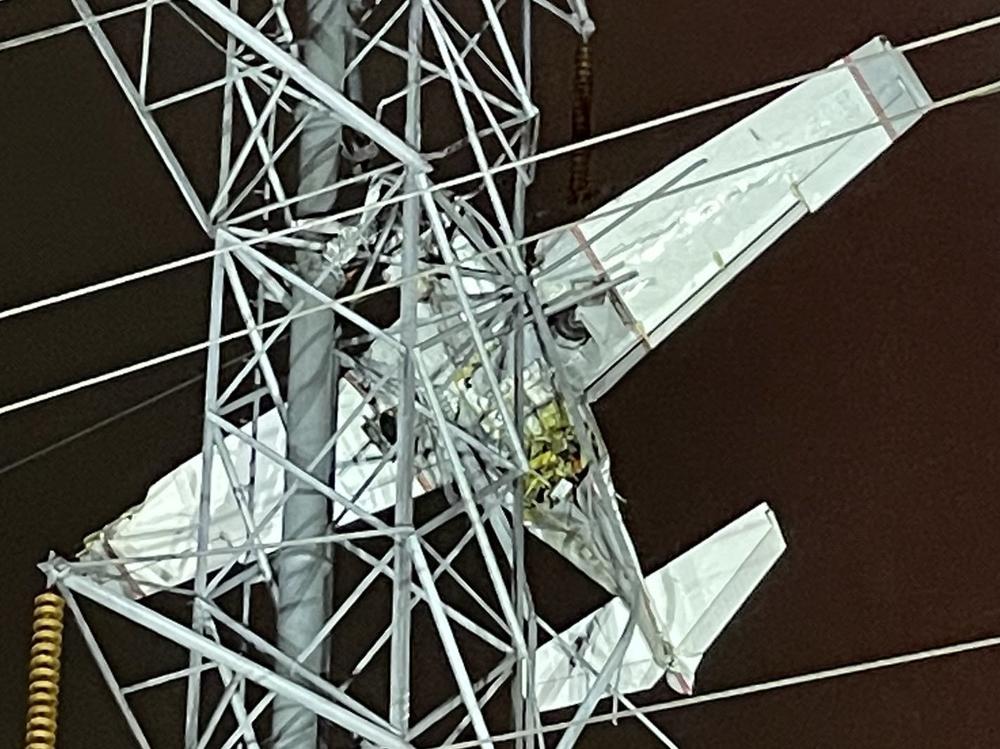 The small plane, pictured, can be seen trapped among the power lines as passengers remain stranded roughly 100 feet in the air.