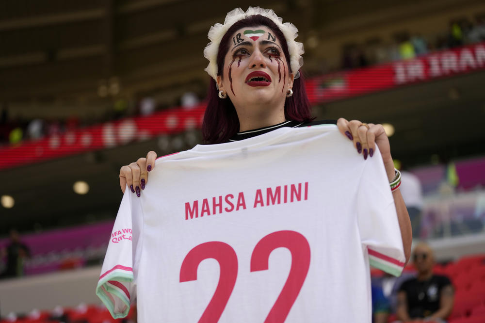 One of Iran's fans cries as she holds a shirt that reads 