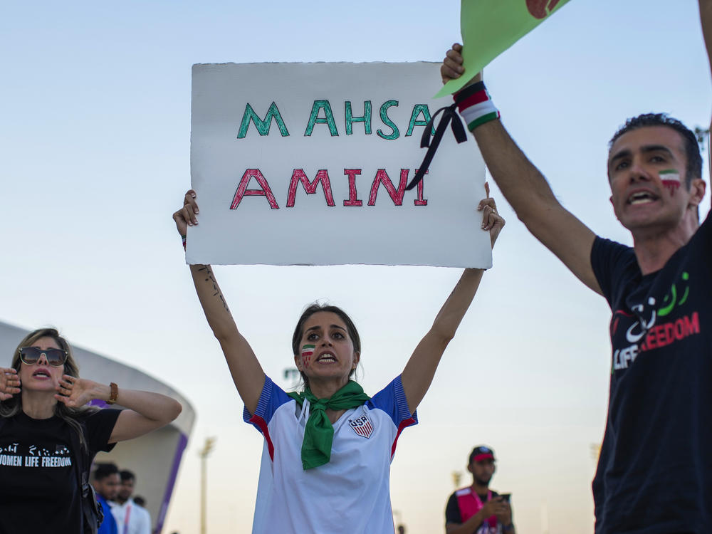 A woman at a protest in Qatar holds up a sign bearing the name of Mahsa Amini, the 22-year-old Iranian woman whose death in police custody sparked a nationwide protest movement.