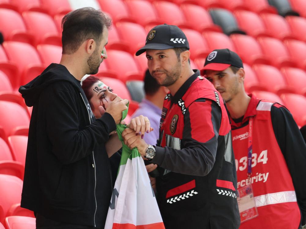 Members of security, right, speak with two Iran supporters as they take away a flag reading 
