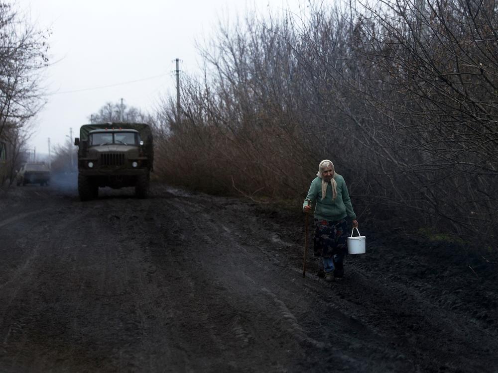 A woman carrying a bucket walks along the road near Bakhmut, on Nov. 27. As temperatures drop, Ukrainians worked to restore power, heat and water supplies after Russian strikes hit key infrastructure.