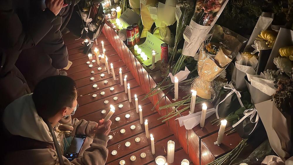 Protesters rallying against a COVID lockdown gather along a Beijing street where with candles are lit for the victims a deadly fire in the city of Urumqi.