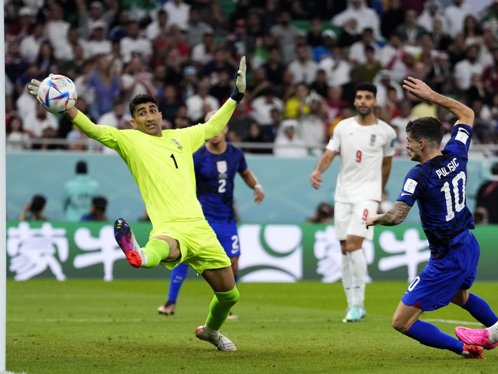 Christian Pulisic of the United States (right) shoots to score his side's first goal past Iran's goalkeeper Alireza Beiranvand during their teams' World Cup match.