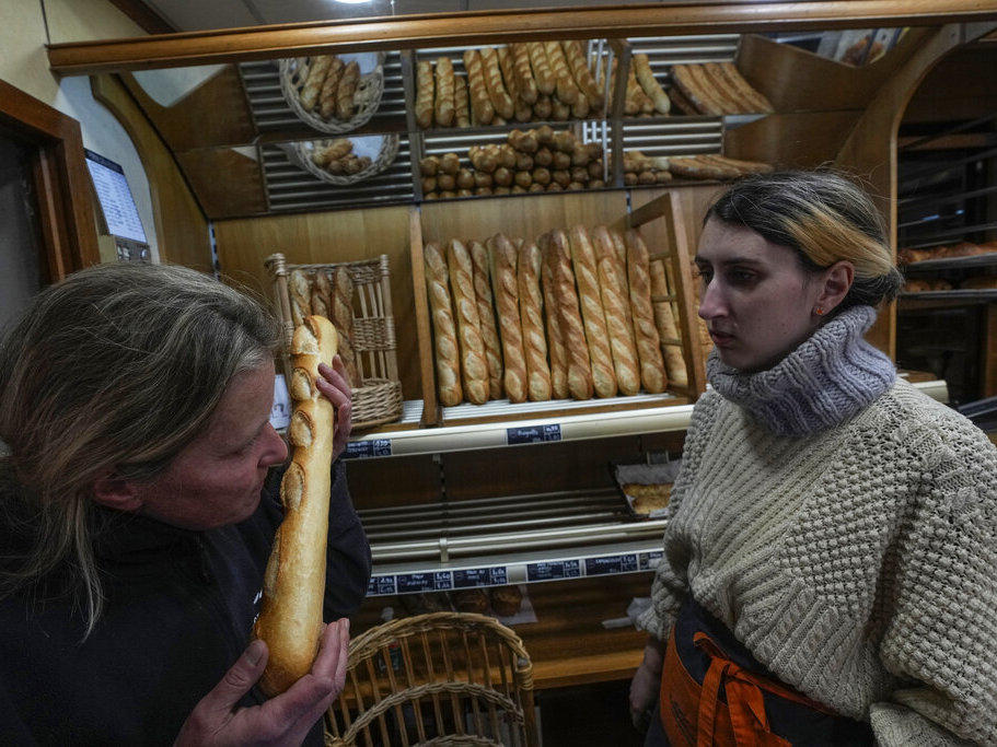 Bakery owner Florence Poirier smells a baguette fresh from the oven Thursday as Mylene Poirier stands next to her at a bakery, in Versailles, west of Paris.