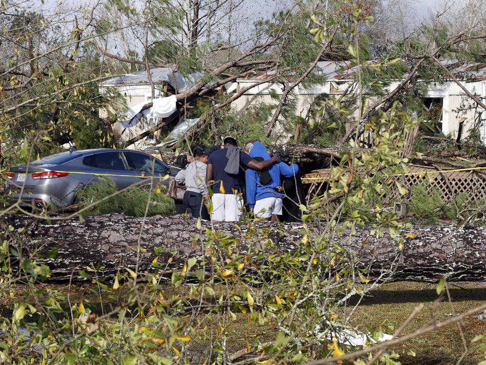 Friends and family pray outside a damaged mobile home on Wednesday in Flatwood, Ala., the day after a severe storm swept through the area. Two people were killed in the Flatwood community just north of the city of Montgomery.