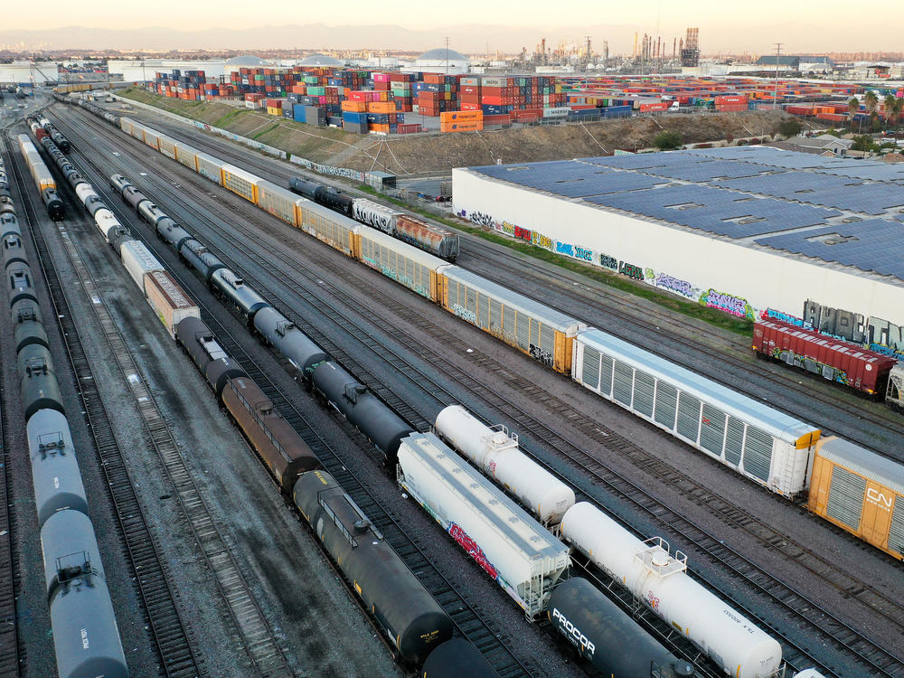 In an aerial view, freight rail cars sit in a rail yard near shipping containers on Nov. 22 in Wilmington, Calif.