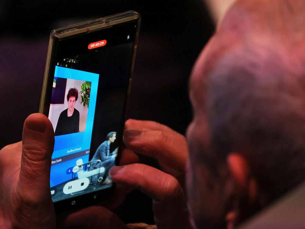 An attendee makes a video as FTX founder Sam Bankman-Fried speaks during the New York Times DealBook Summit in the Appel Room at the Jazz At Lincoln Center on November 30, 2022 in New York City.