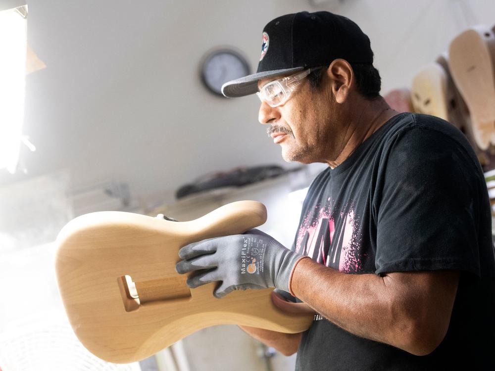 A builder sands the body of a guitar at the Fender factory, in Corona, California, on October 6, 2022. Industries sensitive to rising interest rates have been slowing hiring.