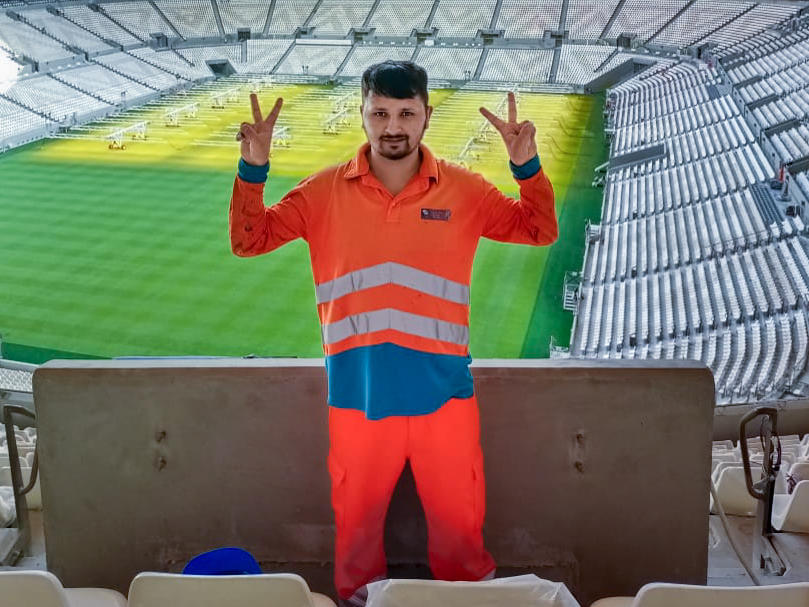 Anish Adhikari, now 26, worked construction jobs in Qatar for 33 months in the lead-up to the World Cup. In this 2021 photo, he poses inside the new Lusail stadium, which he helped build and which will host the World Cup final on Dec. 18. Adhikari says the Nepali agent who got him the job misled him about working conditions in Qatar: 