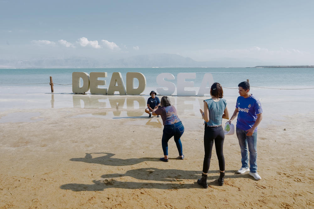Tourists take pictures near a Dead Sea sign near an Israeli hotel resort.