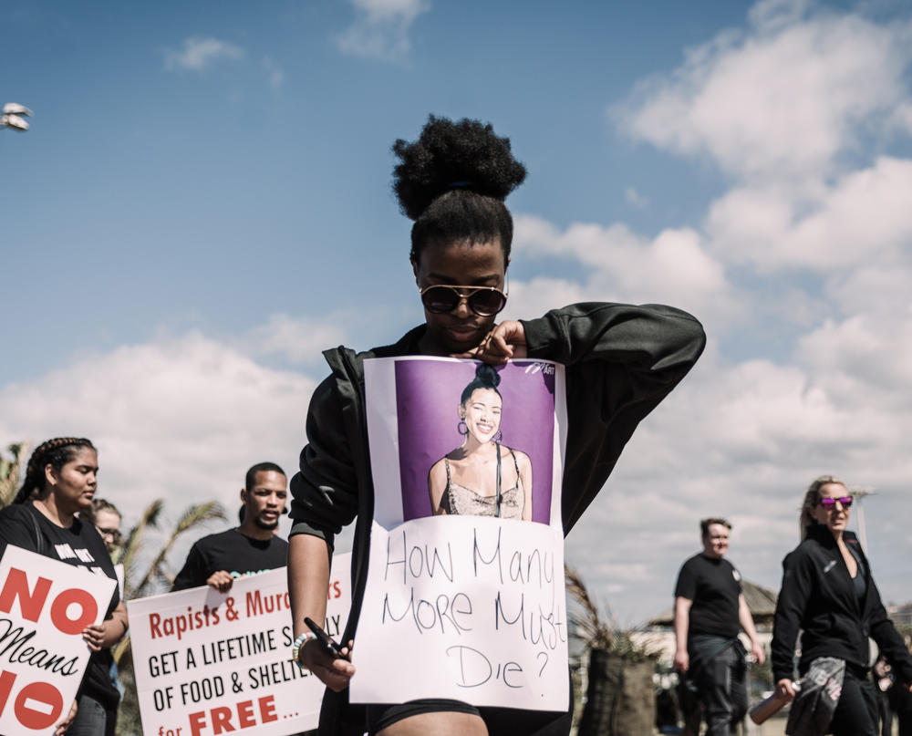 A woman holds a sign as she takes part in a march against gender based violence at the North Beach in Durban in 2019.