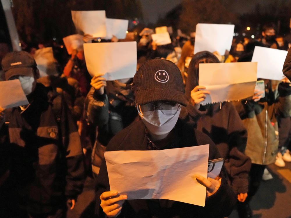 Protesters raise blank papers as they march in protest in Beijing on Nov. 27. The white paper symbolizes a silent protest against the Chinese government's heavy-handed enforcement of free speech.