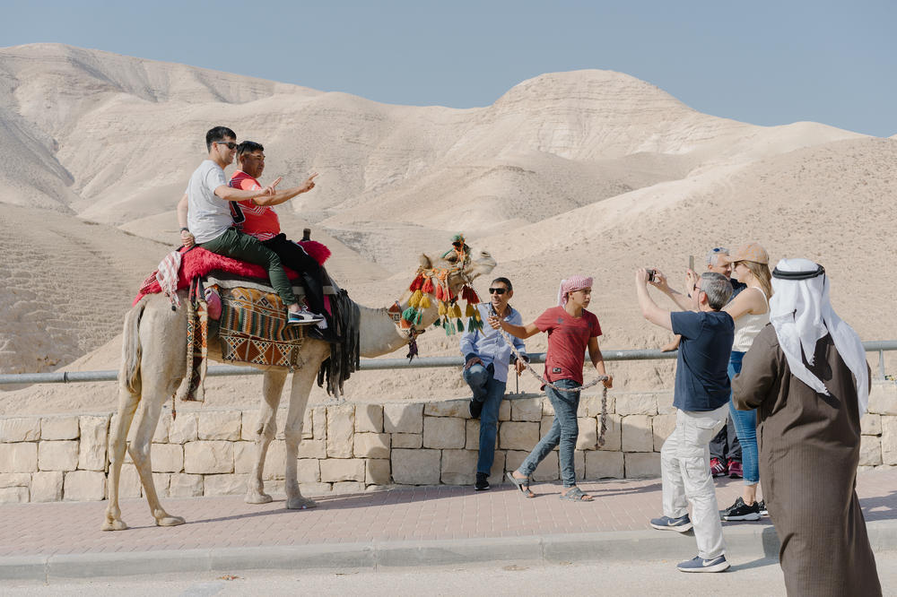 Tourists pose for photographs on camels on the road leading to the Dead Sea in the Israeli-occupied West Bank.