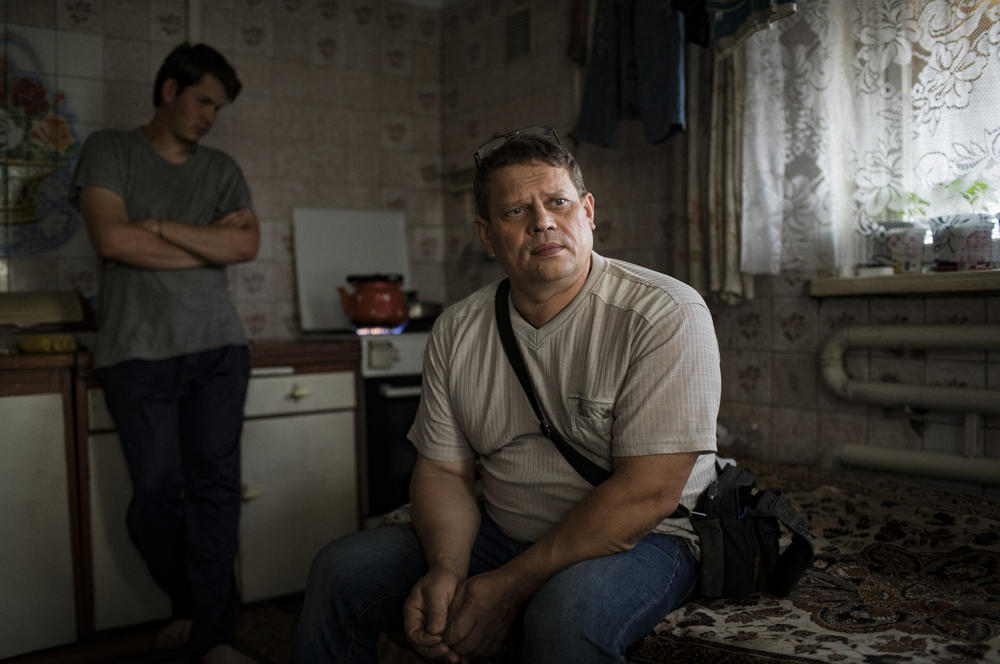 Rodion Lebedev with his son, Dmitry, in their home in Opytne, a suburb of Donetsk, Ukraine, in July 2018. The family was living in a backyard shed, normally used as a second kitchen, at the time, as the house was heavily damaged by shelling. Around 2021, the Lebedevs managed to rebuild their house — only to have it destroyed again a year later.