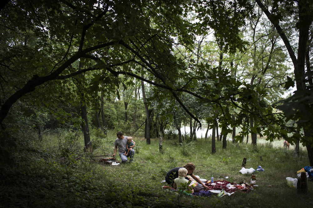 The Grinik family picnics in a forest on the outskirts of Avdiivka in July 2018. From left: Nikolay, Kirill, Olga and Miroslava. They used to picnic in the forest next to their home. When it became a restricted military area, they drove by horse and cart to this meadow. The sound of shelling and gunfire nearby was a constant, but nobody paid any attention.