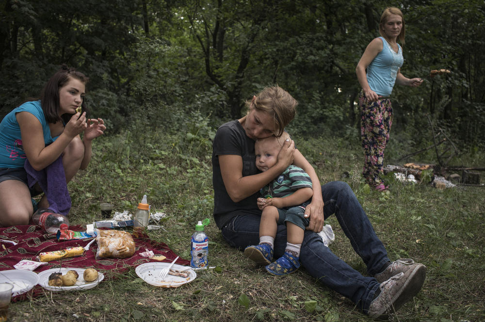 Olga Grinik holds her son, Kirill, during a picnic in a forest on the outskirts of Avdiivka in July 2018, with Olga's sister, Valentina Mountyan (right), and niece, Victoria Mountyan (left).