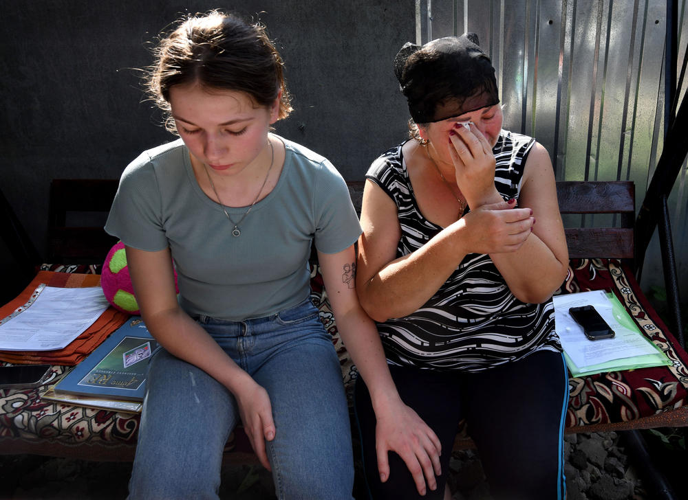 Oleksandr's sister Anya Breus comforts their mother, Oksana, as she cries.