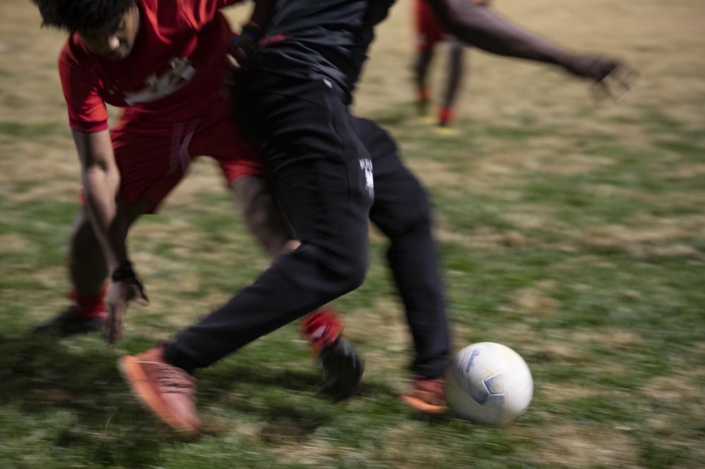 Teen soccer player Raza Palmer and his coach Pierre Hedji compete for the ball.