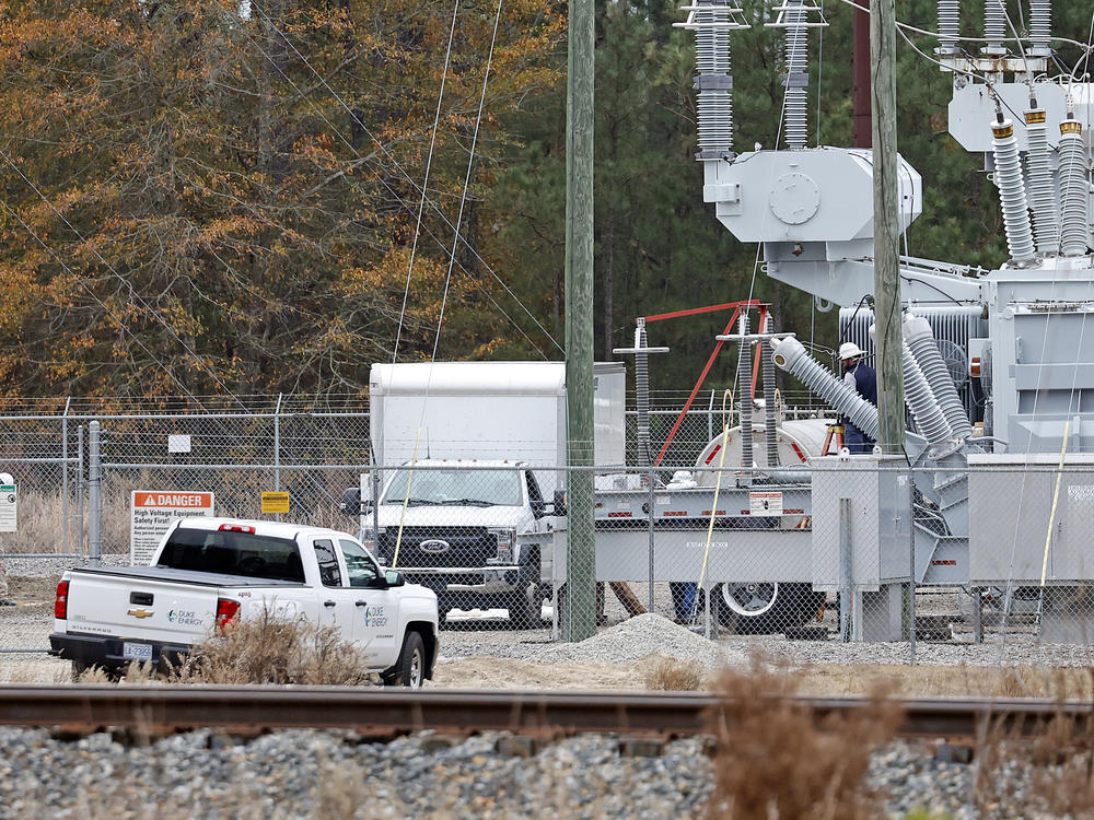 Workers work on equipment Monday at a power substation in West End, N.C., where an attack on critical infrastructure caused a power outage.