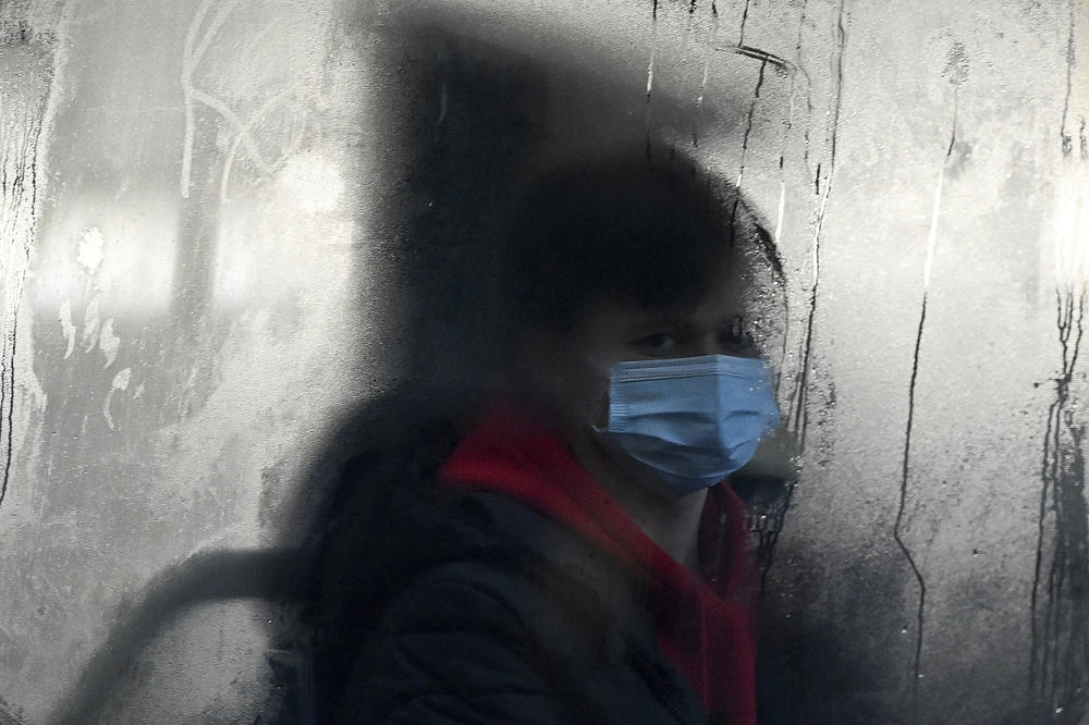 A commuter masks up for a bus ride in Liverpool, England. The omicron variant of the coronavirus has surged in the U.K. and is now dominant in the U.S. as well. There's now data indicating just how severe its symptoms might be.