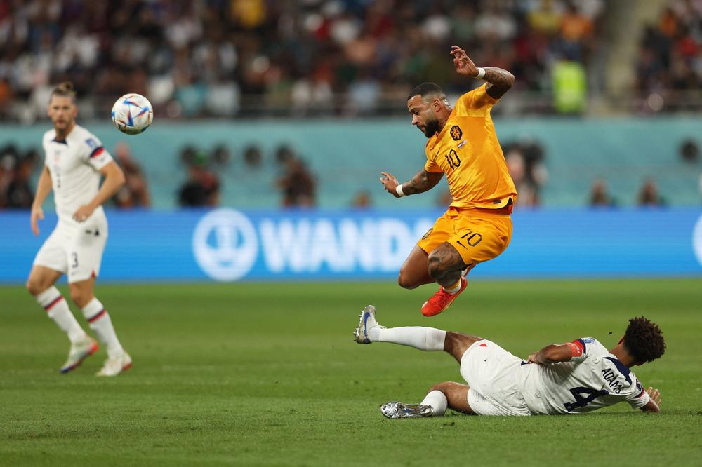 Netherlands' forward Memphis Depay (No. 10) fights for the ball with U.S. midfielder Tyler Adams  (No. 4) during a 2022 World Cup Round of 16 match on Saturday, Dec. 3, at Khalifa International Stadium in Doha, Qatar. Netherlands won the match.