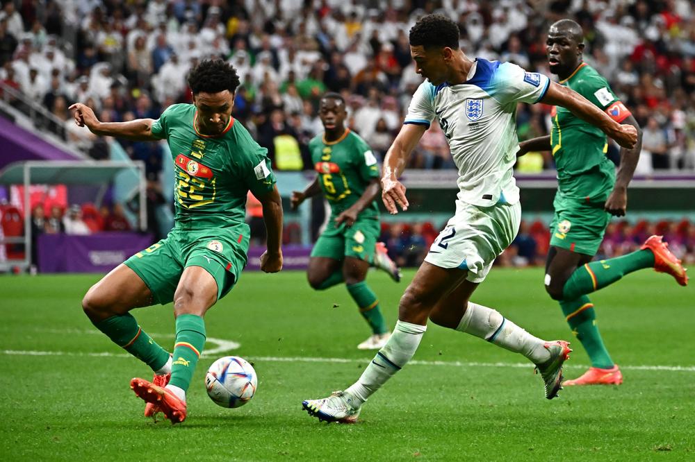 England's midfielder Jude Bellingham (right, No. 22) fights for the ball with Senegal's defender Abdou Diallo (No. 22) during a 2022 World Cup Round of 16 match on Sunday, Dec. 4, at the Al-Bayt Stadium in Al Khor, north of Doha, Qatar.