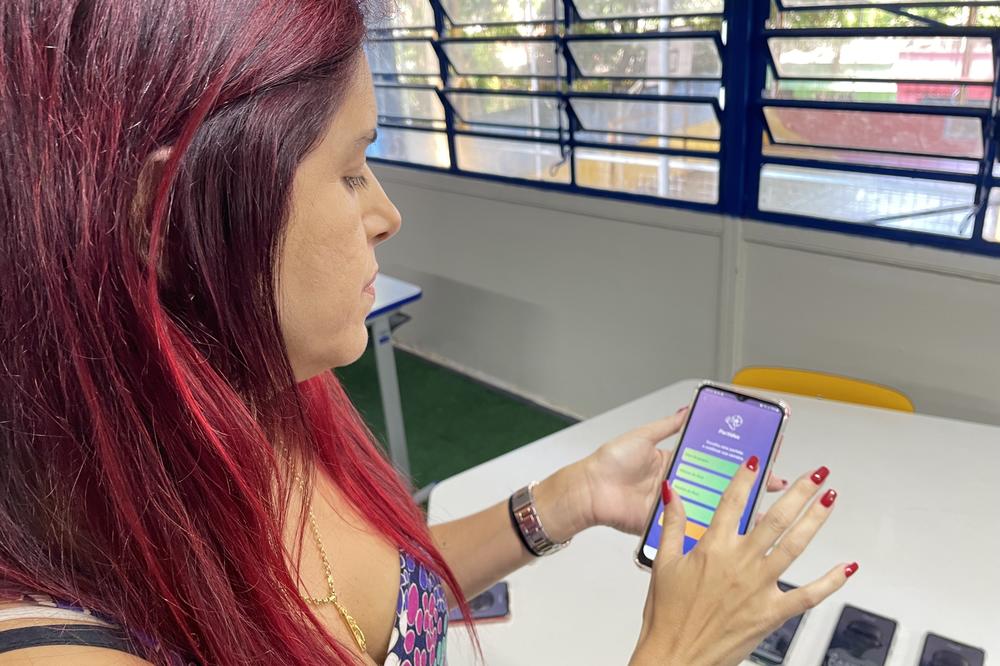 First-grade teacher Ubiara de Santana shows the BASE app developed by the Vini Jr. Institute. The institute donated 10 cellphones with the app to Escola Municipal Paulo Reglus Neves Freire, a public elementary school in Vinícius Júnior's hometown.