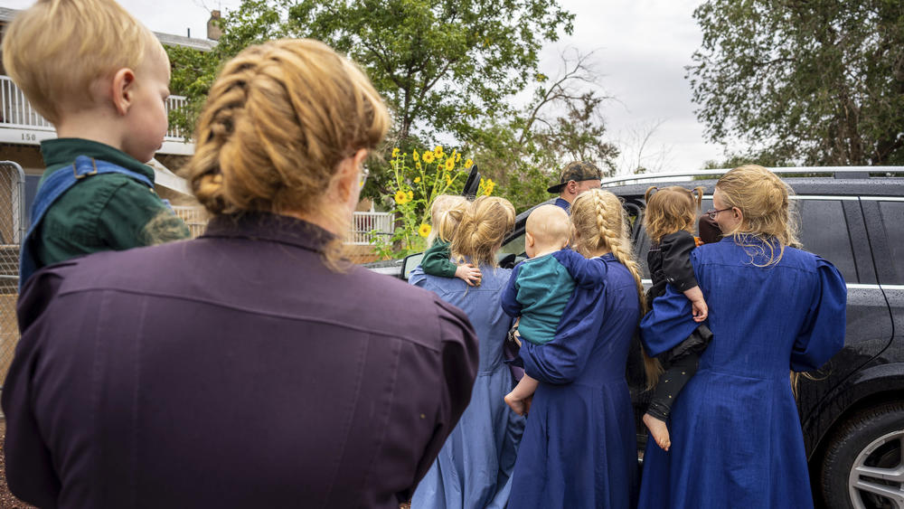 Family and followers of Samuel Bateman gather around as he calls from police custody following his arrest in Colorado City, Ariz.,in September.