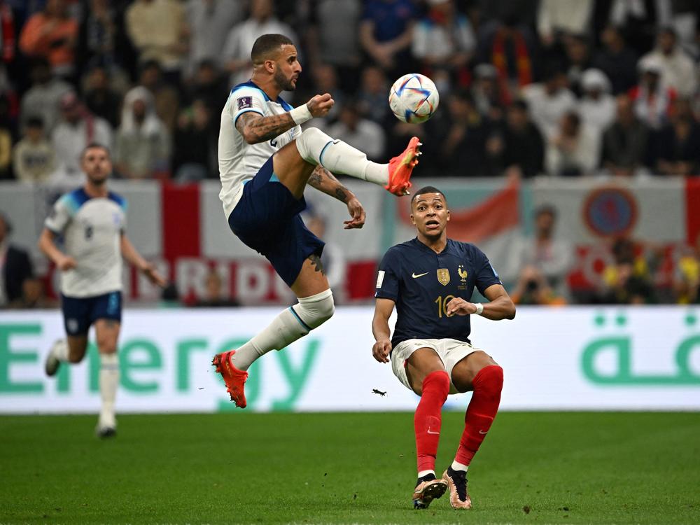 France forward Kylian Mbappe (#10) fights for the ball with England defender Kyle Walker during the World Cup quarterfinal match between England and France at the Al-Bayt Stadium in Al Khor, Qatar on December 10, 2022.