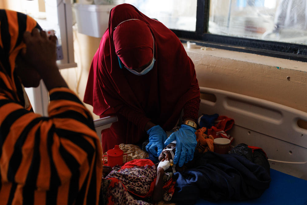 A nurse adjusts Deeqle Ibrahim's nasal feeding tube as he lies on a hospital bed, while his mother, Meral Ibrahim, looks on at Banadir Hospital in Mogadishu on Monday. Deeqle is suffering from severe malnutrition, and his mother had to travel more than 60 miles from their home village to the hospital in Mogadishu. Deeqle is two years old, but he weighs less than 12 pounds.