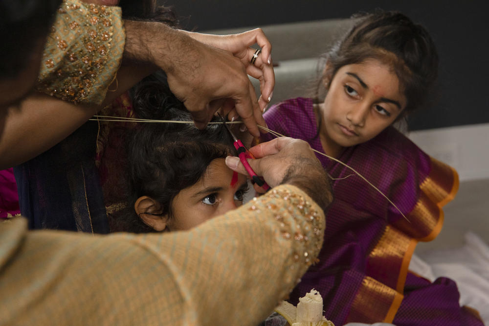 Kayla Patil, 7, watches her 3-year-old brother Eshaan's haircutting ceremony at their home in Vienna, Va. In a traditional Hindu <em>mundan</em> ceremony, a priest cuts a child's first hairs off to symbolize letting go of their past life. When Maansi was little, the strands of her hair cut during her <em>mundan</em> ceremony were spread near her mother's childhood home in Delhi, along the Ganges.