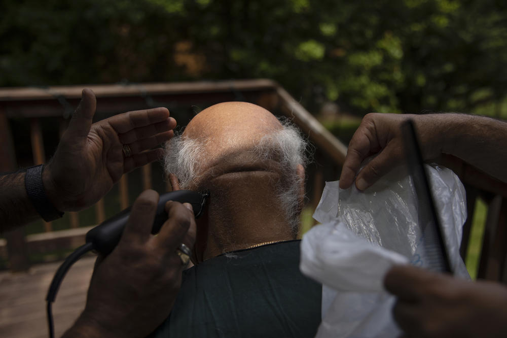 In his mourning, Maansi's father and uncle shave her grandfather's head and trim his facial hair in June 2021, in Harrington Park, N.J. In Hindu tradition, this hair cutting is seen as a symbol of grief and a mark of respect for the departed soul.