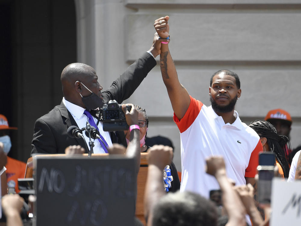 Attorney Benjamin Crump (left) holds up the hand of Kenneth Walker during a rally on the steps of the Kentucky State Capitol in Frankfort, Ky., on June 25, 2020. Walker, the boyfriend of Breonna Taylor who fired a shot at police as they burst through Taylor's door the night she was killed, has settled two lawsuits against the city of Louisville, his attorneys said.