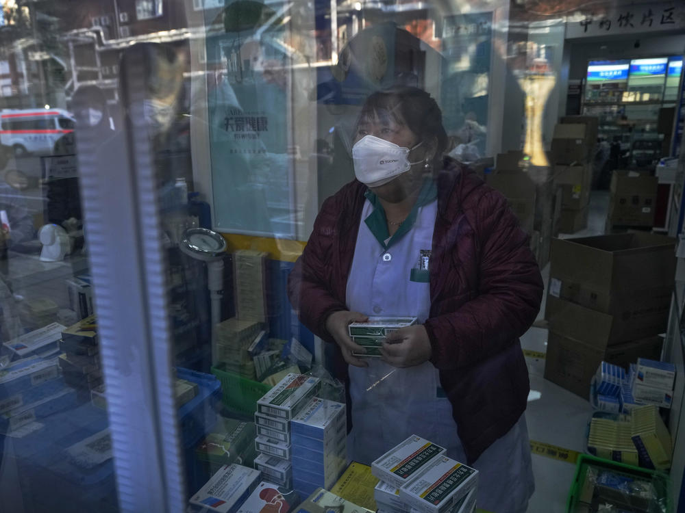 Residents are reflected on a door panel as they wait in line to buy medicine at a pharmacy in Beijing on Tuesday.