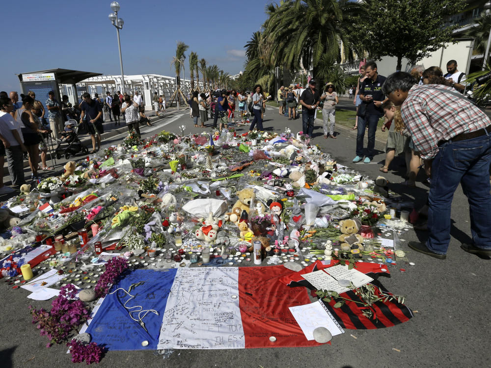 People look at flowers placed on the Promenade des Anglais at the scene of a truck attack on July 18, 2016, in Nice, southern France. A French court on Tuesday convicted eight people charged in connection with the Bastille Day attack that killed 86 people.